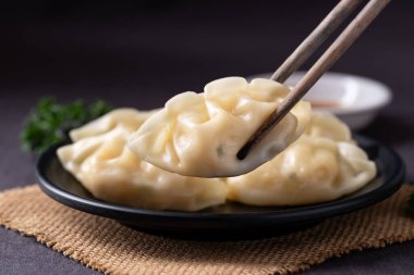 Yemek çubuğu ve susam yağı soslu enfes buharda pişirilmiş hamur köftelerini yakın.