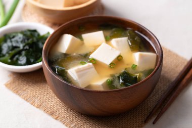 Yumuşak tofu ile sağlıklı Japon miso çorbası ve yemek çubuklarıyla ahşap bir kasede yosun.