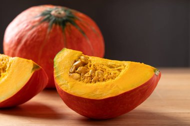 Tahta bir arka planda dilimlenmiş portakallı Kuri kabağı (Hokkaido kabağı), pişirmeye hazırlanıyor.