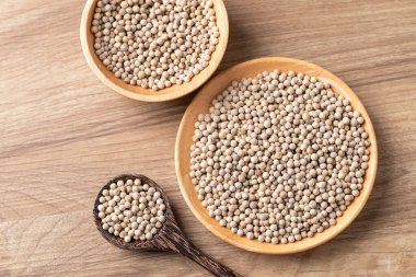 Tahta bir kasede beyaz biber ve ahşap arka planda kaşık manzarası, temel baharatlar ve yemek pişirmek için baharatlar.