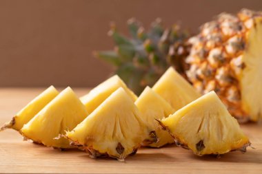 Kahverengi ahşap zemin üzerinde taze olgun ananas dilimleri yemeye hazır, Tropik yaz meyvesi