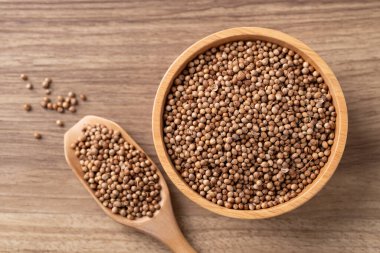 Tahta bir kasede kişniş tohumları ve ahşap bir arka planda kaşık Tayland gıda malzemelerinin üst görüntüsü.