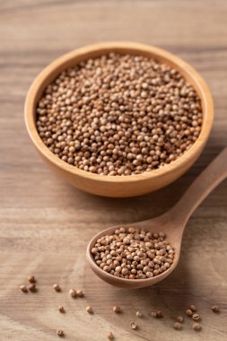 Tahta kaşıkta kişniş tohumu ve ahşap arka planda kase, Tayland yemeği malzemeleri.