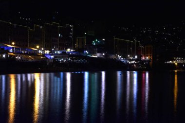 Gece ışıkları denizi yansıtıyor.