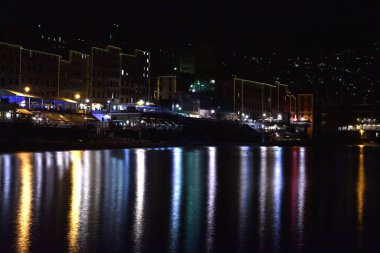 Gece ışıkları denizi yansıtıyor.