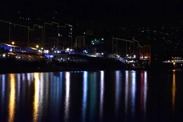 Gece ışıkları denizi yansıtıyor.