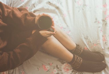 Evindeki yatağında bir fincan kahve içerken ısınan ve rahatlatan genç bir kadının en iyi görüntüsü.