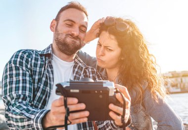 Kumsalda tatilde olan genç çift fotoğraf makinesiyle komik bir selfie çeker - sevgili ve sevgili rahatlama anlarını fotoğraf çekerek paylaşır - sevgi ve tasasız konsept - sıcak filtre
