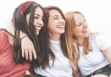 Bir grup mutlu, çok kültürlü kadın turist eğleniyor ve gülümsüyor. En iyi arkadaşlar, arkalarında deniz varken tatilin tadını çıkarıyorlar. Arkadaşlık ve eğlence kavramı.