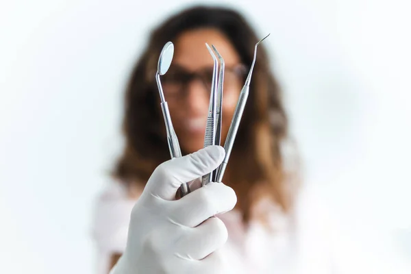 Close up of medical dentist tools with smiling female doctor in background