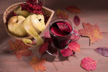Sonbahar içkisi koyu ahşap arka planda şarap, sonbahar yaprakları, viburum üzümleri ve elmalar hasır vazoda. Yatay yönelim