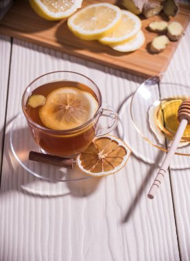 Limonlu, ballı ve zencefilli vitamin çayı cam bir fincanda, beyaz arka planda. Yaklaş. Dikey yönelim.