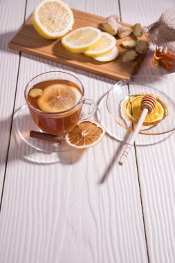 Tahta kesim tahtasında limon, bal ve zencefilli cam bardakta vitamin çayı, beyaz arka plan. Yaklaş. Dikey oryantasyon. Boşluğu kopyala