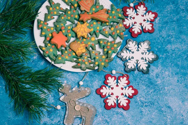 Plate with handmade Christmas gingerbread, pine branches and Christmas decorations on a blue background. Horizontal orientation. — Stock Photo, Image