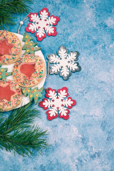 На синем фоне тарелка с рождественским печеньем ручной работы и рождественскими снежинками. Вертикальное направление. Копирование пространства — стоковое фото