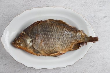 Güzel beyaz bir tabakta kızarmış balığın yakın çekimi. Hafif arkaplan, deri döşeme