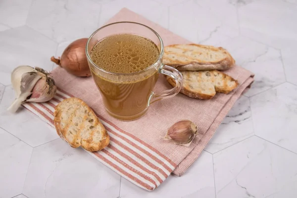 Bouillon de viande dans une tasse en verre sur une serviette pour le déjeuner sur un fond clair. Le concept de saine alimentation. — Photo