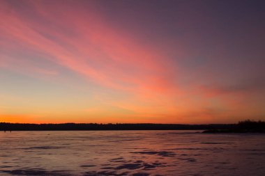 Donmuş bir gölün üzerinde gün batımı. Kış arkaplanı. Yatay yönelim