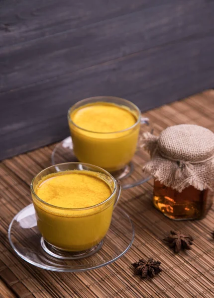 Deux tasses en verre avec une boisson de désintoxication asiatique tendance à base de lait d'amande avec des épices au curcuma. Du lait doré. Espace de copie — Photo