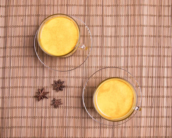 Two cups of Golden Milk on a straw mat. Asian Vegan Detox Drink with Turmeric Spices