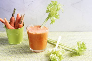 Bir bardak taze sıkılmış havuç suyu ve yeşil peçetede bir kova havuç. Paleo diyeti kavramı.