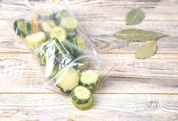 Gefrorene Zucchini werden aus der Tüte auf einen hellen Tisch gegossen. Konzept Tiefkühlkost Stockbild