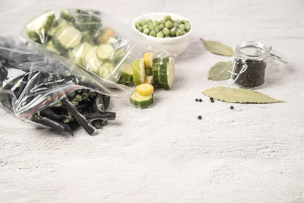 Bolsas de verduras congeladas frijoles de cadena y calabacín, así como guisantes verdes congelados sobre un fondo claro. Concepto de alimentos congelados Imágenes de stock libres de derechos