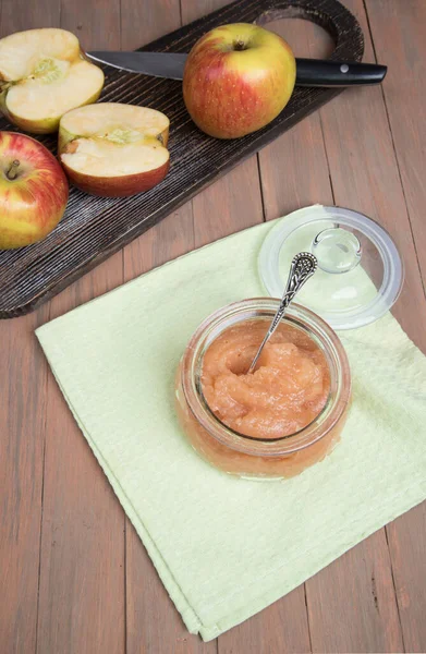 A can of Apple puree and sliced fresh apples on a wooden chopping Board on a wooden background . Flat lay.Vertical orientation.