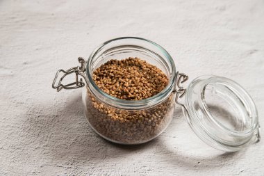 Hafif bir masada karabuğday dolu cam bir kavanoz. Sağlıklı beslenme gevrekleri. Rus mutfağı.