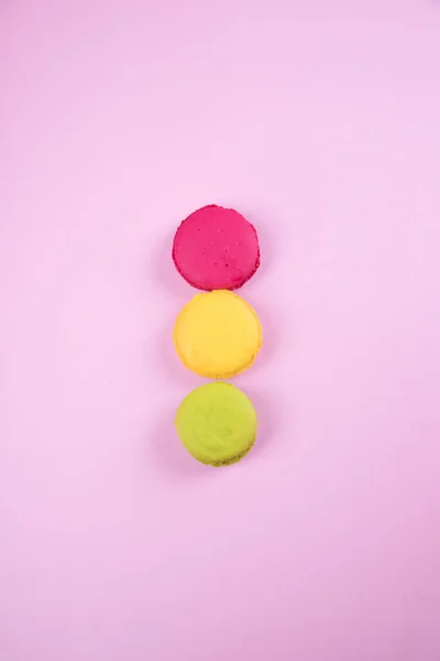 Colocado en fila de acuerdo con los colores del semáforo, macarrones galletas sobre un fondo de papel rosa. Copiar espacio — Foto de Stock