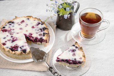 Parlak masanın üzerinde beyaz bir tabak var. İçinde ev yapımı böğürtlenli turta var..