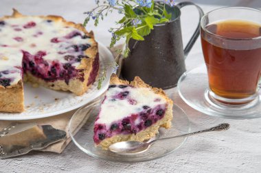 Taze ev yapımı turta, böğürtlen ve çay dolu parlak bir masa..