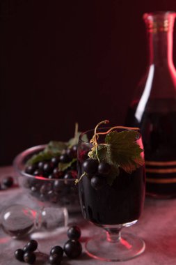 Camında böğürtlen ve ev yapımı siyah üzümlü likör olan bir bardağın yakın çekimi. Alçak tuş