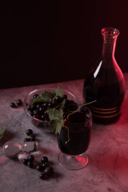 Karanlık bir arka planda, bir sürahide ev yapımı kuşüzümü likörü..