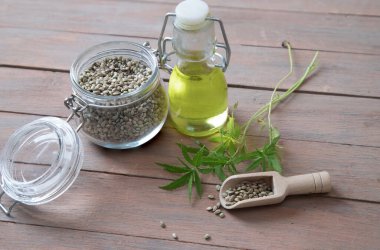 Tahta kaşıkta kenevir tohumu, ahşap masada kenevir yağı ve kenevir sapı. Alternatif yağ