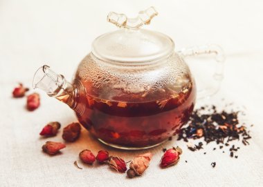 Kuru kırmızı küçük gül siyah çay cam çaydanlık, çay içme, Aromatize çiçekler, tablo kaba keten bezi ile; Tonda