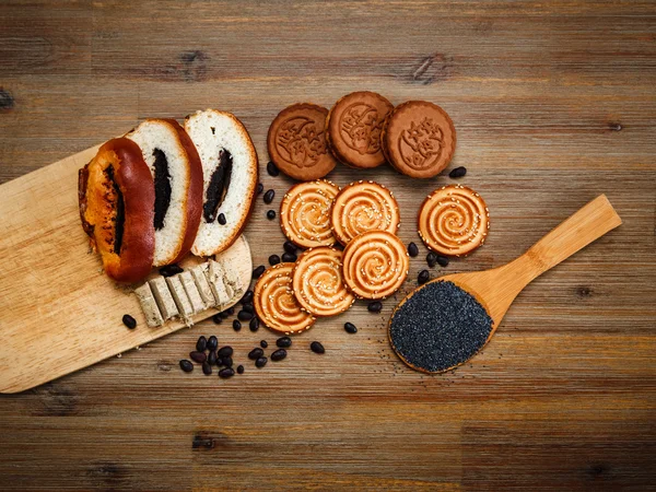 There are Pieces of  Roll with poppyseed,Cookies,Halavah,Chocolate Peas,Tasty Sweet Food on the Wooden Background,Top View — Stock Photo, Image