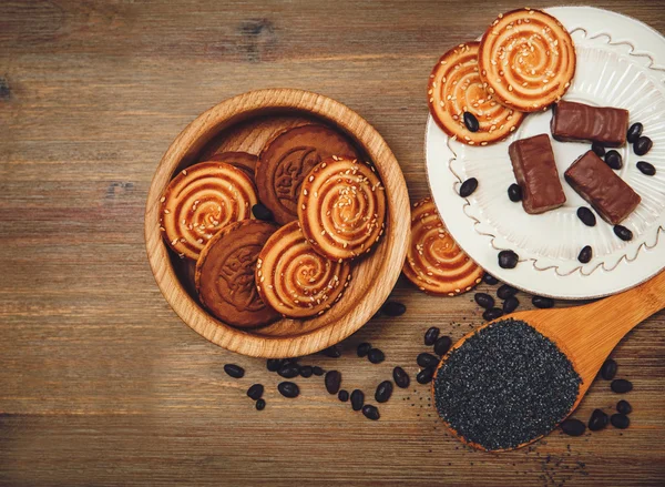 Tam są ciasteczka, cukierki, czekolada groch, Mak; Porcelanowe talerzyk, smaczny słodki żywności na drewniane tła, widok z góry — Zdjęcie stockowe
