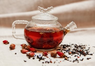 Siyah çay cam çaydanlık, çay içme, Aromatize çiçekler, kuru kırmızı küçük gül kaba keten masa örtüsü