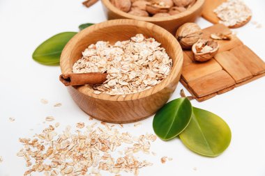 Ceviz ve haddelenmiş yulaf Sinnamon yapışır, ahşap desteği, kaşık, yeşil yaprakları, beyaz arka plan üzerinde sağlıklı taze organik gıda ile ahşap plakalar içinde