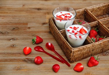 Ahşap Masa üzerinde Plastik Kaşık ile Rattan Kutusunda Yoğurt, Kırmızı Taze Çilek İki Bardak.Kahvaltı Organik Sağlıklı Lezzetli Food.Cooking Vitaminler 