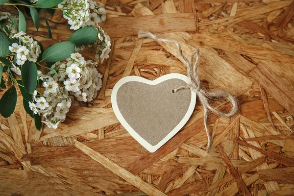 Kleine hart kaart met witte bloemen en groen laat op de wensen van de houten Background.Celebrations textuur — Stockfoto