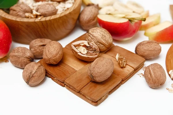 Υπάρχουν μήλο, καρύδια στα ξύλινη πινακίδα, πυροστιά, υγιή φρέσκα βιολογικά τρόφιμα στο λευκό φόντο — Φωτογραφία Αρχείου