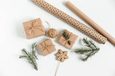 Noel yatağında çam dalları, hediye kutuları, kahverengi sicim, zencefilli ekmek ve beyaz arka planda ambalaj kağıtları vardı. Noel hazırlığı, hediye paketleme konsepti