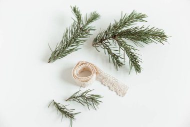 Beyaz arka planda örülmüş dantelli köknar dalları olan bir Noel yatağı. Noel süslemesi