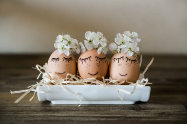 Yuvasında yüzleri olan kahverengi elli yumurtalar, çiçek açan çiçekler. Paskalya, tatil konsepti, tasarımın için hediye kartı, metin için yer. Minimalist.
