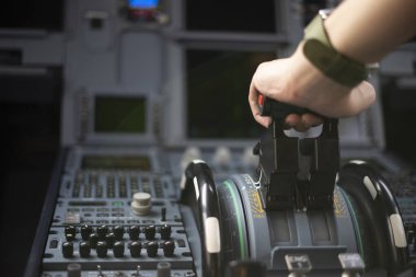 Ticari bir uçağı uçuran pilotun kırpılmış elleri, kokpit görüşü, ellerin kapalı olması. Kaptan el, ticari uçağın gaz pedalında hızlanıyor. Seçici odak.