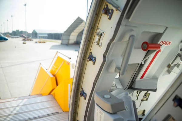 Open door to a large airliner as seen from inside. Aircraft door frame, door handle and door barrier strap. Selective focus.