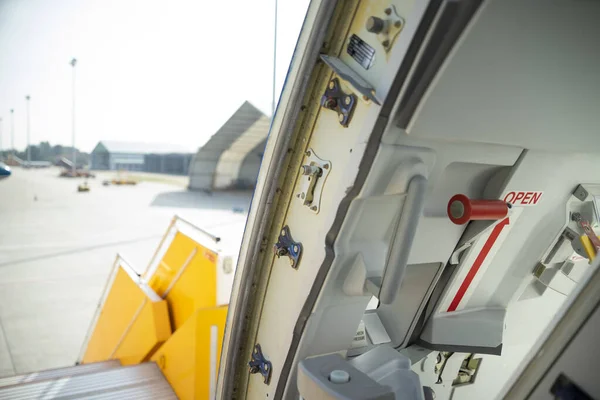 Open door to a large airliner as seen from inside. Aircraft door frame, door handle and door barrier strap. Selective focus.
