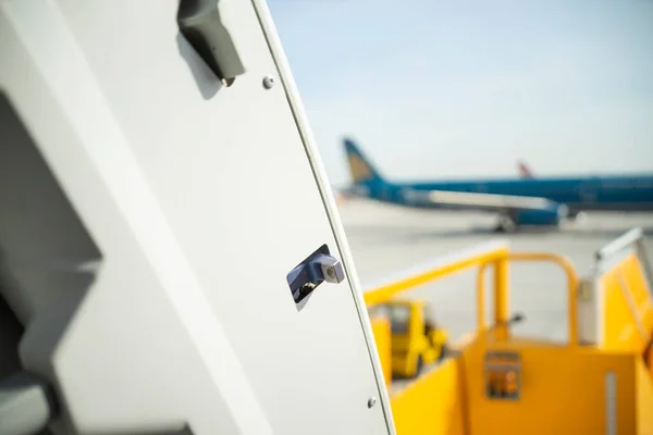 Open door to a large airliner as seen from inside. Aircraft door frame, door handle and door barrier strap. Selective focus.